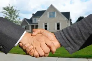 A handshake with your realtor with a house in the background.